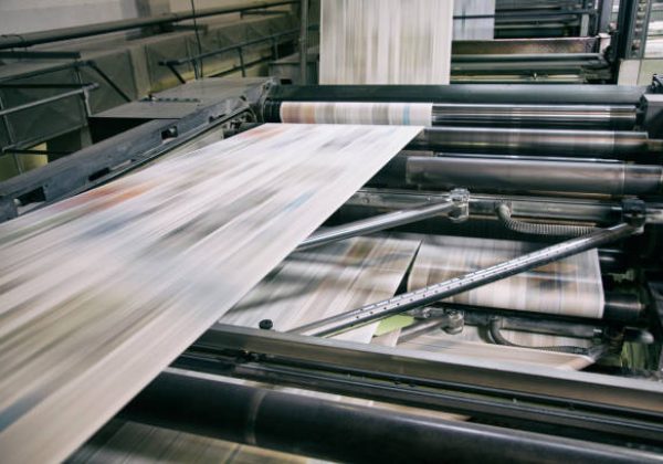Newspapers being printed in printing press.